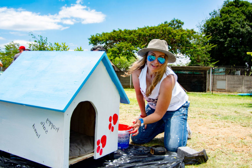 Woman can be seen painting a dog house